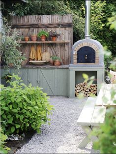 an outdoor pizza oven with potted plants on the side and a bench in front