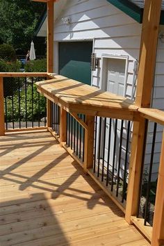 a wooden deck with metal railings next to a white house