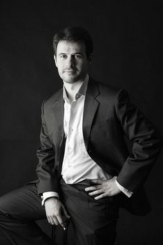 a black and white photo of a man in a suit posing for the camera with his hands on his hips