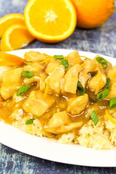 a white plate topped with rice covered in chicken and oranges next to an orange slice