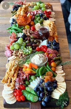 a long wooden platter filled with lots of different types of fruit and veggies