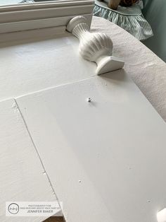 a close up of a piece of white paint on a window sill with a vase in the background