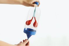 a person is holding a blue and red liquid in a glass bottle with a toothbrush