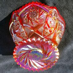 an orange glass bowl sitting on top of a black cloth covered floor next to a red vase