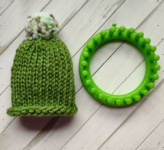 a green knitted beanie next to a green plastic ring on a white wooden surface