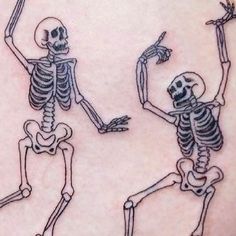 two skeleton tattoos on the back of a woman's shoulder, one is pointing at another