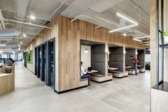 an office with wood paneling and black booths on the walls, along with people working at their laptops