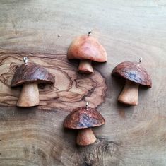 four wooden mushrooms sitting on top of a piece of wood