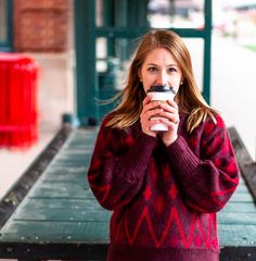 a woman in a red sweater holding a coffee cup