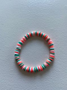 a red, green and white beaded bracelet sitting on top of a white surface