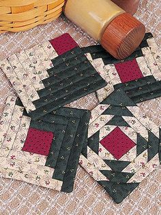 four quilted coasters on a table with a rolling pin