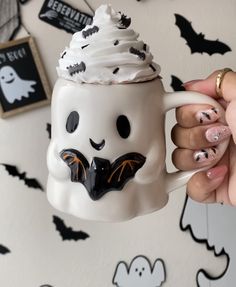 a person holding a coffee mug with white frosting and black sprinkles on it