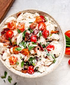 a white bowl filled with salad next to tomatoes