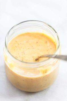 a glass jar filled with food sitting on top of a white counter next to a spoon