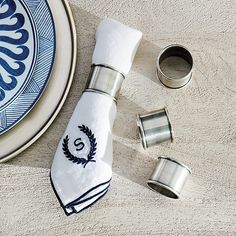 a blue and white plate with some napkins on it next to two silver cup holders