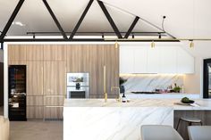 an open kitchen with marble counter tops and white cabinets, along with modern appliances in the background