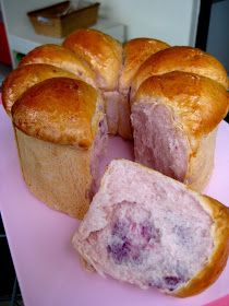 a large loaf of bread sitting on top of a pink countertop next to some rolls