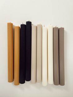 four different colored sticks are lined up on a white surface and one is black, the other has brown