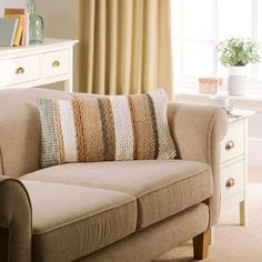 a living room with a couch, table and window in the backround area