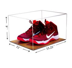 a pair of basketball shoes in a clear display case on a wooden floor with measurements