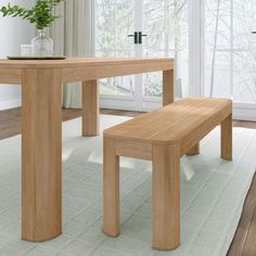 a wooden table with two benches in front of it on a white rug next to a window