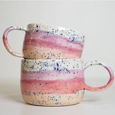 two pink and blue coffee mugs sitting side by side on top of each other