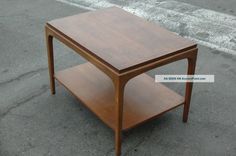 a small wooden table sitting on top of a cement road next to a street sign