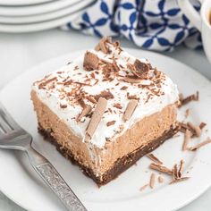 a piece of cake on a plate with a fork and cup of coffee in the background