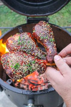 someone is holding up some meat on the skewer over an open fire pit