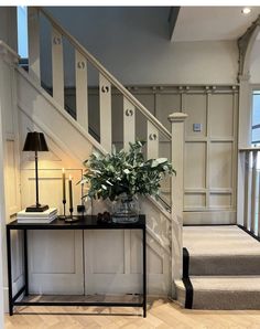 a vase with flowers sitting on top of a table next to a stair case in a house