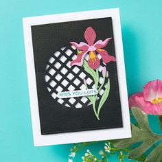 a close up of a flower on a card with flowers in the foreground and a blue background