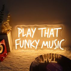 a neon sign that says play that funky music next to an old record and flower pot