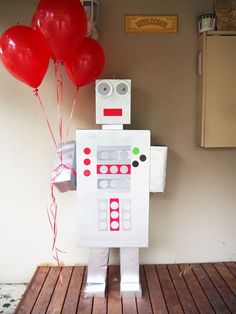 a paper robot holding red balloons on top of a wooden floor