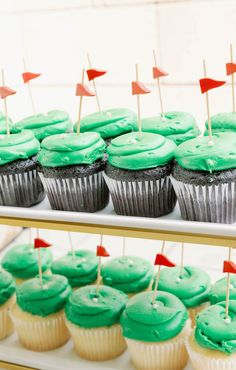 cupcakes with green frosting and small red flags on sticks in front of them