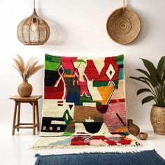 a multicolored rug is on the floor next to some potted plants and two wicker baskets