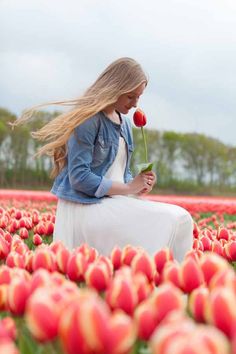 a woman is sitting in a field of tulips