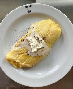 a white plate topped with an omelet covered in cream