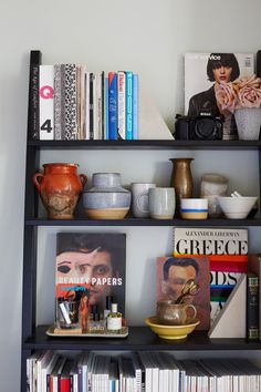 a book shelf filled with books, magazines and vases on top of each other