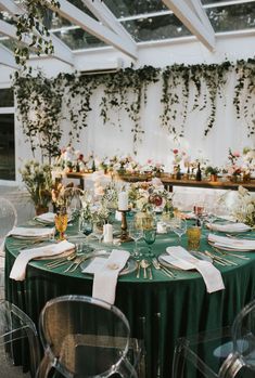 the table is set with green linens and place settings for guests to sit at