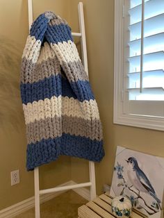 a blue and white knitted blanket sitting on top of a ladder