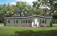 a small green house sitting on top of a lush green field next to trees and flowers