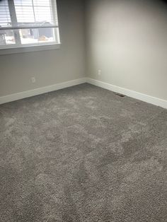 an empty room with carpeted flooring and a window in the corner that is open