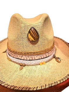 Sand-colored straw panama hat, decorated by hand.
The central element of the hat is a Eye of the Tiger drop-shaped located in the center of the dome.
as a garnish I applied some white and camel colored trimmings, and a strip of snakeskin. 
The hat is enriched with a removable chain made up of small brass balls, tiger eyes and various pendants. The brim is hand-sewn with alternating golden and brown thread.
Size: 57/59
Material: 100% straw made in Italy.
Designed and handmade by Gipsy Fashion Wea Handmade Western Straw Hat, Gold Wide Brim Bohemian Fedora, Handmade Straw Western Hat Bands, Handmade Straw Hat Bands, Western Style, Handmade Western Straw Hat Bands, Handmade Straw Hats For Rodeo, Handmade Straw Hat Bands In Country Style, Brown Bohemian Panama Hat For Summer, Handmade Western Fedora For Summer