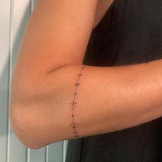 a woman's arm with an arrow tattoo on the left side of her arm