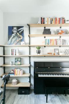 a black piano sitting in front of a book shelf filled with books