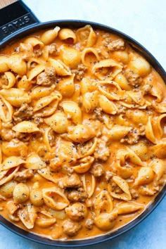 a skillet filled with macaroni and cheese on top of a blue counter