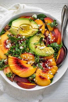 a white bowl filled with peaches, avocado and feta cheese on top