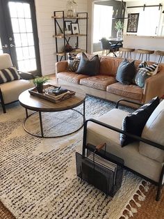 a living room with couches, chairs and rugs on the floor in front of windows