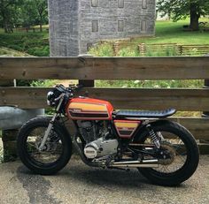 an orange and black motorcycle parked next to a wooden fence