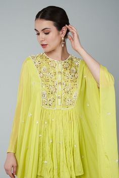 Yellow tunic with floral bead embellishments on yoke and cape sleeves. Paired with embroidered band gharara.
Components: 2
Pattern: Embellished
Type Of Work: Bead
Neckline: Round
Sleeve Type: Cape
Fabric: Chiffon, crepe, georgette
Color: Yellow
Other Details: 
Gathered details
Placket detailing
Note: The clutch held by the model is not for sale
Occasion: Wedding - Aza Fashions Pista Green Straight Kurta With Gota Work, Anarkali Gota Work Kaftan For Wedding, Pista Green Dress With Gota Work, Designer Gota Work Dresses For Transitional Season, Transitional Designer Dresses With Gota Work, Transitional Season Embellished Georgette Sharara, Embellished Anarkali Style Georgette Palazzo Set, Pista Green Floor-length Dress With Gota Work, Elegant Pista Green Dress With Gota Work